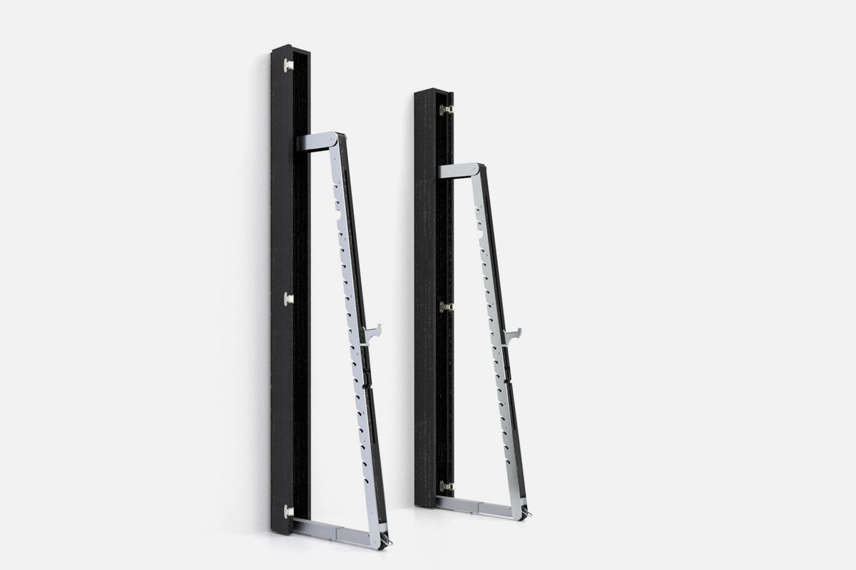 Two wall-mounted squat racks in black wood, one folded shut and one opened to a silver ladder