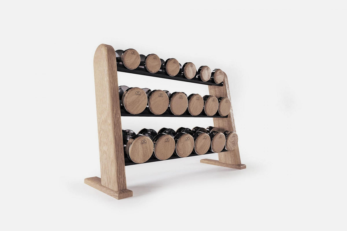 Three-tier weathered light-wood rack holding nine pairs of nickel-plated dumbbells with pale end caps