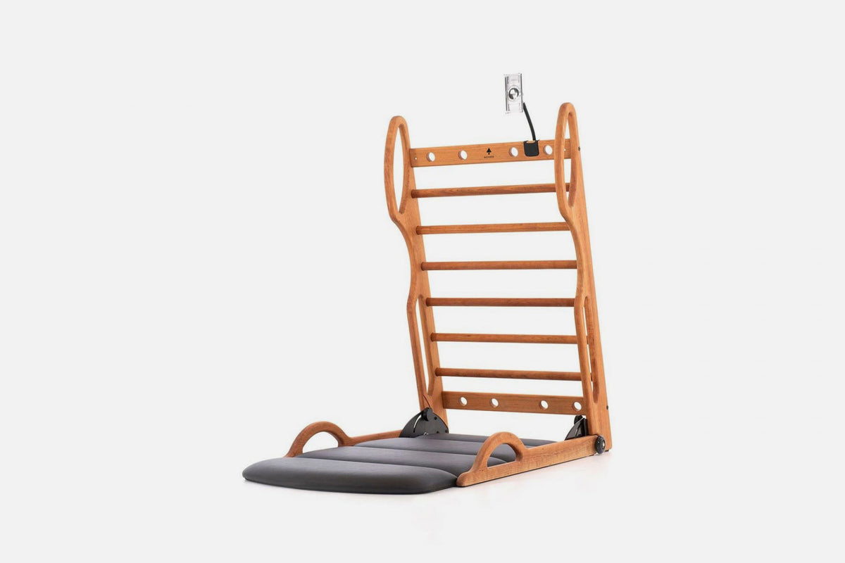 Open stretch station in warm golden wood with horizontal rungs and a dark fold-out mat