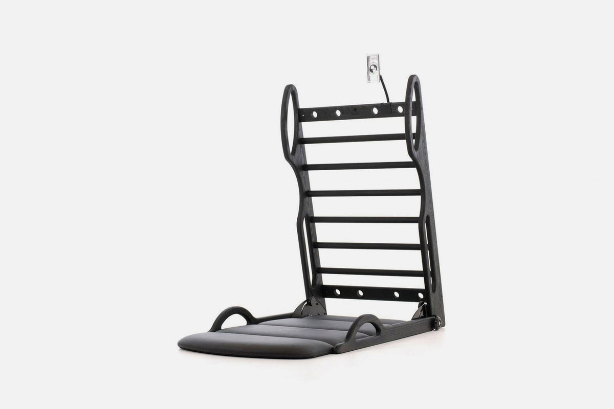 Open stretch station in black wood with horizontal rungs and a dark fold-out mat