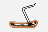 Side view of a curved manual treadmill with a warm golden wood frame, black slats, and a raised black handlebar