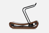 Side view of a curved manual treadmill with a dark brown wood frame, black slats, and a raised black handlebar