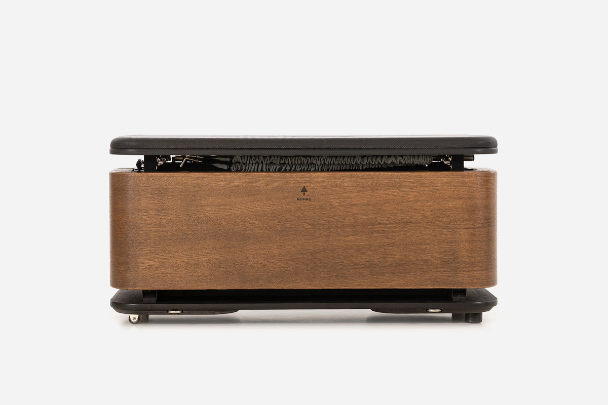 Front view of a medium-brown storage bench with the padded lid raised and resistance bands visible inside